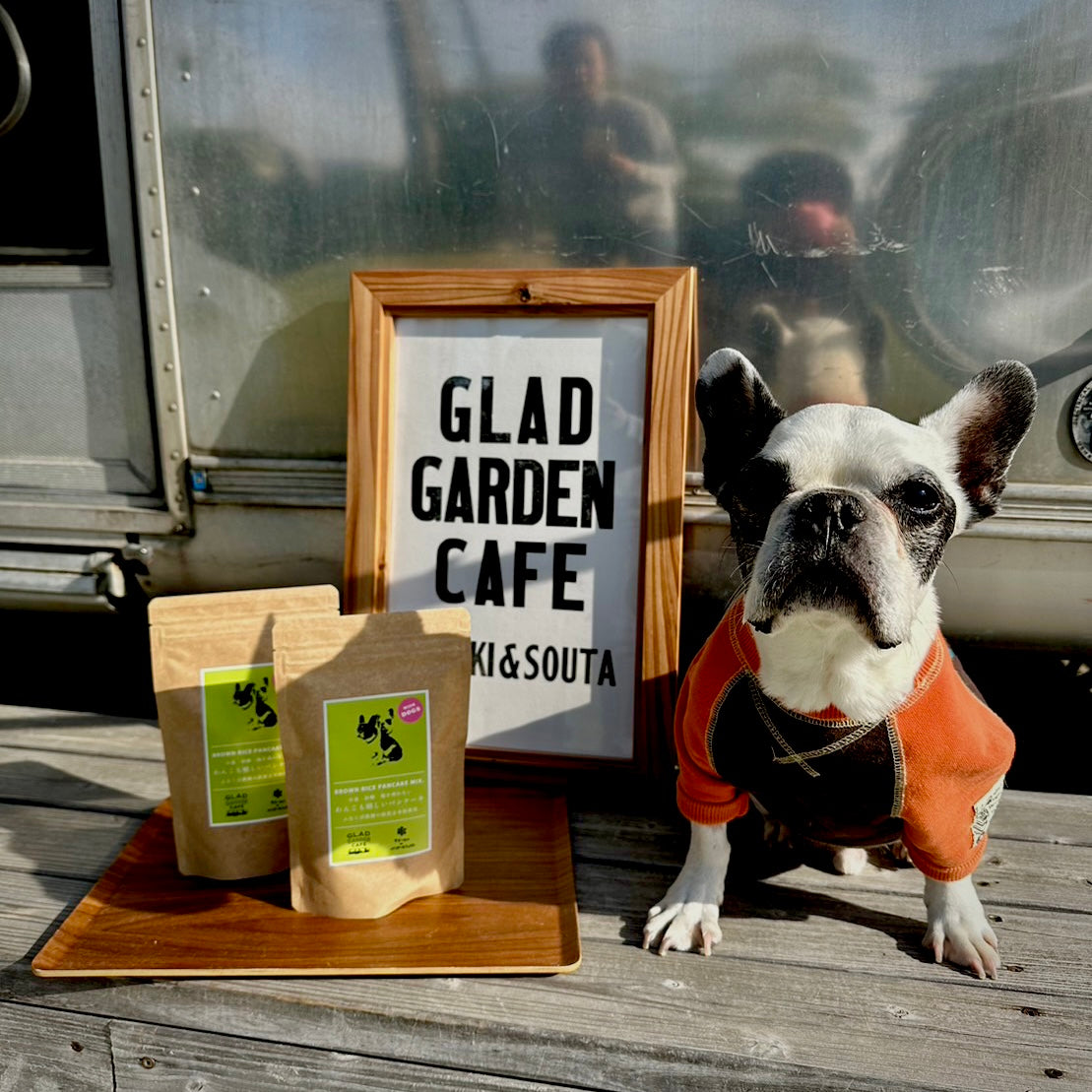 GLAD GARDEN CAFEの看板と一緒に並んだ『わんこも嬉しいパンケーキミックス』と、オレンジの服を着たフレンチブルドッグ