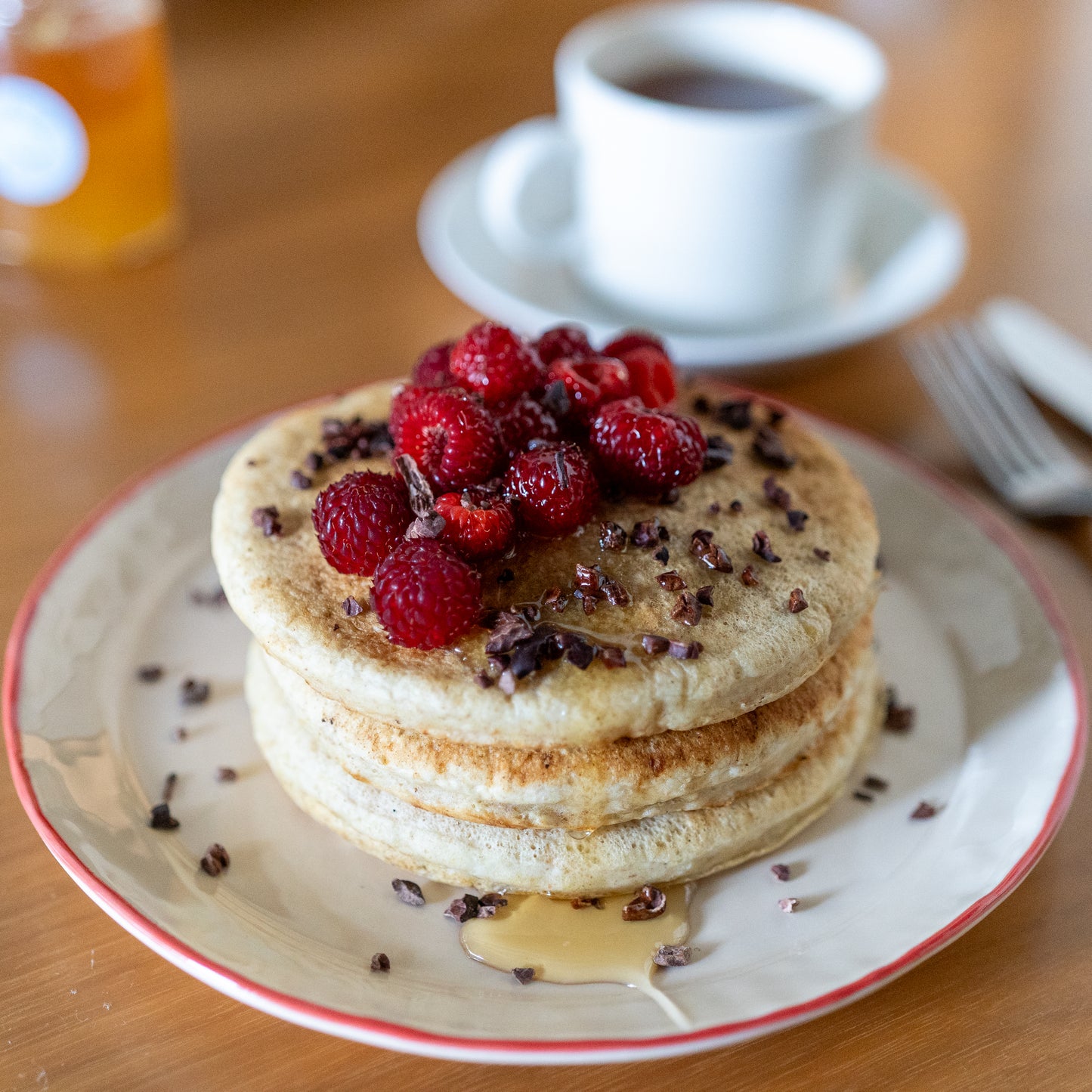 パンケーキにラスベリーとカカオニブをトッピングして、、ハチミツをたっぷりとかける。